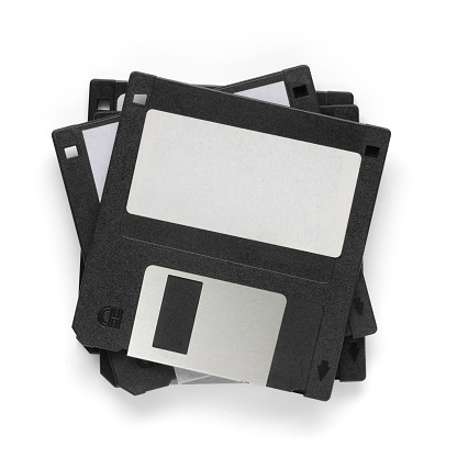 Stack of old black floppy disks - on top of with blank badge, isolated on white background