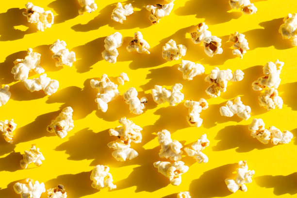 istock Scattered cinema popcorn on yellow background overhead 1356196392