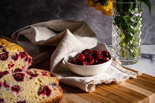 Cranberry quick bread or cake is traditional holiday fare typically served with coffee or tea. Shown here freshly sliced on a cutting board with a side dish of cranberry sauce.