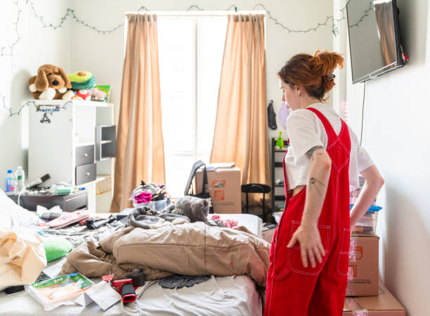 teenage girl in her room on the floor on scattered clothes before cleaning near the bed lies