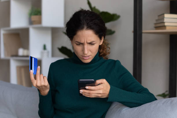 Concerned lady looking on smartphone having finance stolen from card stock photo