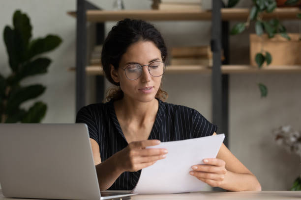 istock Serious young hispanic female manager in glasses study project documentation 1356201205