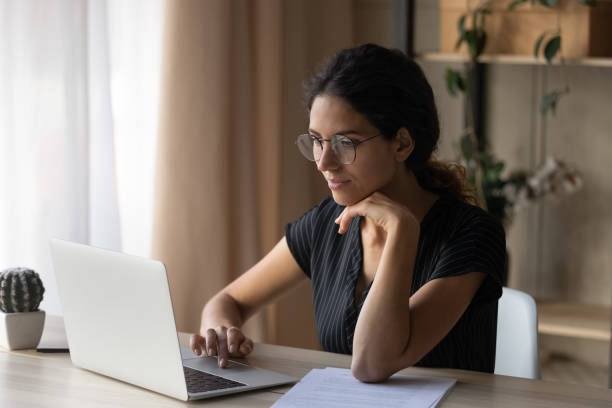 istock Young hispanic woman sit by desk work online by laptop 1356201209