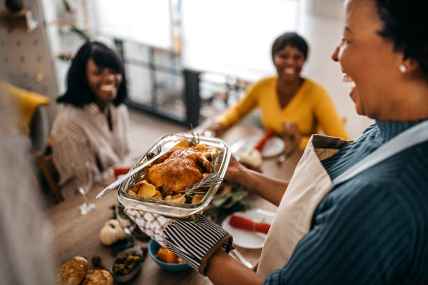 frau serviert gebratenen truthahn an freunde zu hause - christmas food dinner turkey stock-fotos und bilder