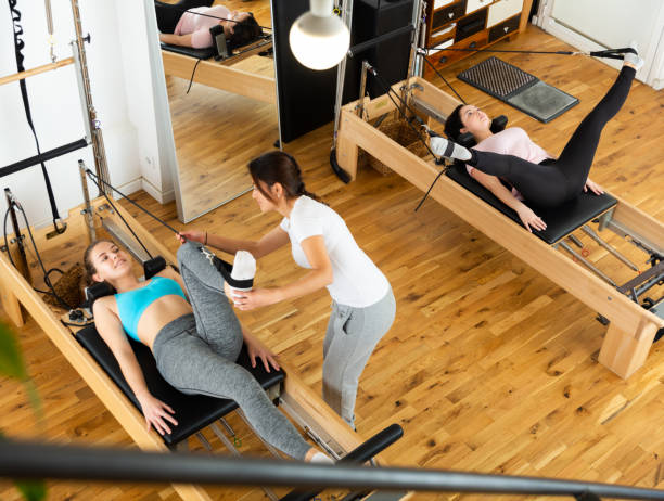 istock Top view of women practicing Pilates on reformer with trainer in studio 1356202689