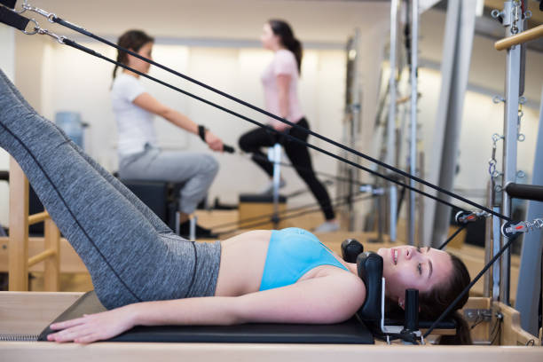 femme exerçant une rotation d’incendie criminel au gymnase en utilisant des lits de pilates - pilates machine photos et images de collection