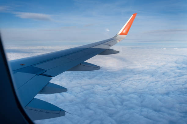 istock Classic image through aircraft window onto wing. Flight view over clouds 1356203922