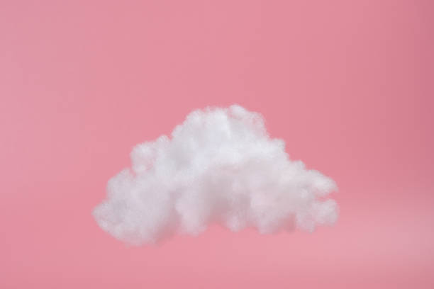 white decorative cloud on pink background white decorative cloud of cotton fibers or wadding on a pink background. Trendy image on pink background cotton cloud stock pictures, royalty-free photos & images