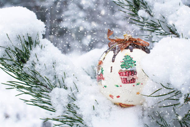 A colorful Christmas ball hung on a snow-covered Christmas tree twig stock photo