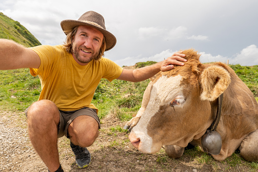 He smiles at the camera,  cattle cow beside him\nAppenzelerland canton, Switzerland