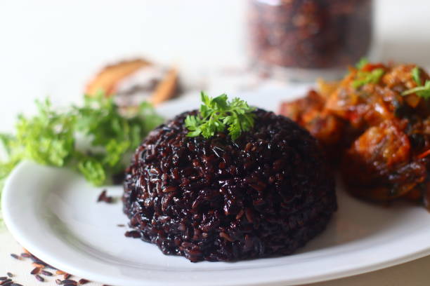 schwarzer reis pulao. eine eintopf-reiszubereitung mit schwarzem reis, ghee und gewürzen. serviert mit hähnchenbraten. schwarzer reis, auch verbotener reis genannt, ist der nahrhafteste reis - rice paddy rice food short grain rice stock-fotos und bilder