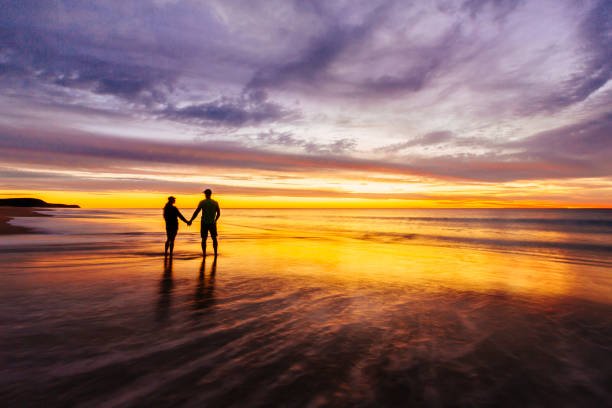 istock A couple holding hands on the beach at sunrise. 1356210610