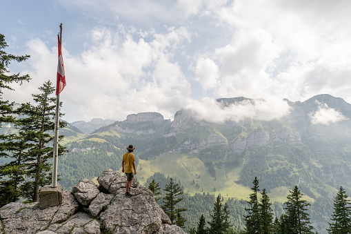 Rear view of man hiking on mountain ridge looking at spectacular view in Appenzellerland Canton, Switzerland