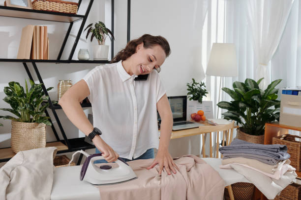 istock Ironing Businesswoman Calling Colleague 1356213165
