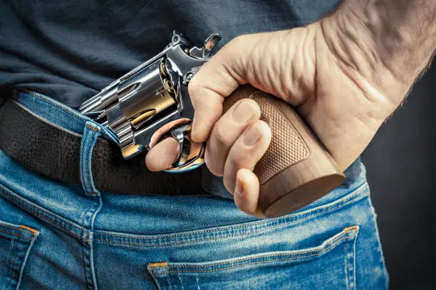 man hiding a revolver behind his back