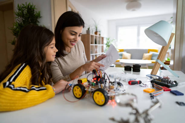 istock Caucasian mother and her daughter looking at instructions while trying to make a prototype of robotic car 1356215387