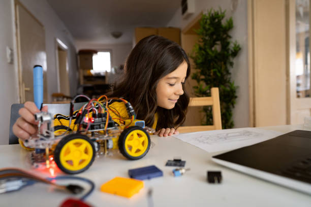 istock Smart school girl, looking at instructions while making a prototype of an self-driven robotic car 1356215536