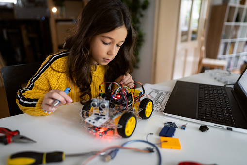 School girl, testing her prototype of an autonomous self-driven robotic car, she making for a school science project