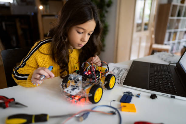 Dedicated schoolgirl, observing the prototype of robotic car, she testing stock photo