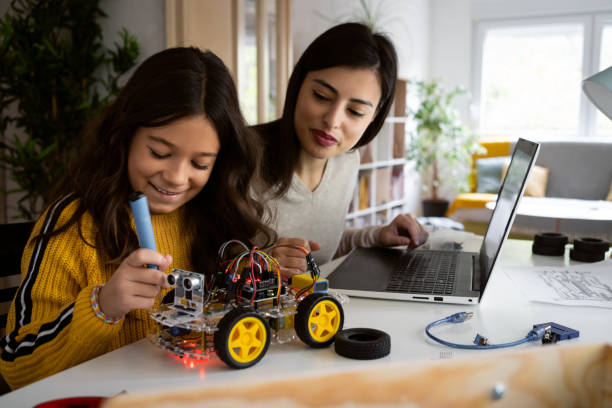 Caucasian mother observing her smart daughter while doing a school science project Curious and smart schoolgirl, helping her mother who work in STEM field, an engineer and computer programmer to make an autonomous self-driven robotic car with sensors school science project stock pictures, royalty-free photos & images