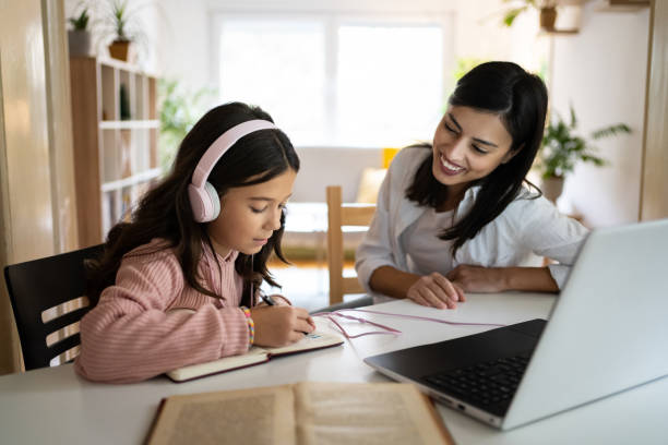 istock Dedicated schoolgirl doing her homework while female tutor observing her 1356217005