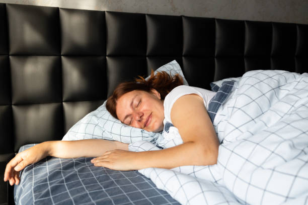 istock Young woman sleeping in bed on pillows 1356218629