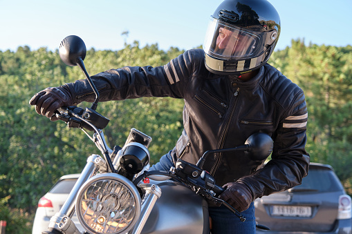 Motorcyclist with helmet and leather jacket riding on the bike