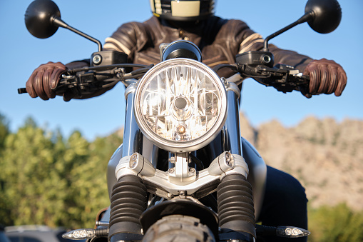 Front view of a motorcycle with headlight on and unrecognizable person