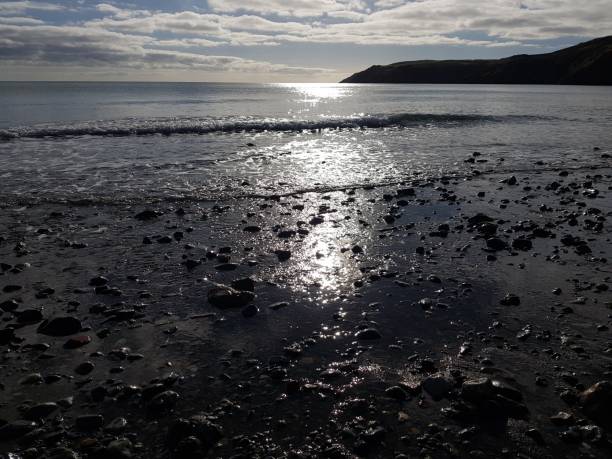 sunset on beach, sun reflecting off the sea - coastline pebble the lleyn peninsula wales imagens e fotografias de stock