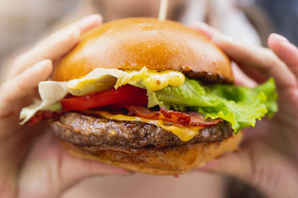 istock Close-up tasty burger. Female hands hold hamburger. 1356221773