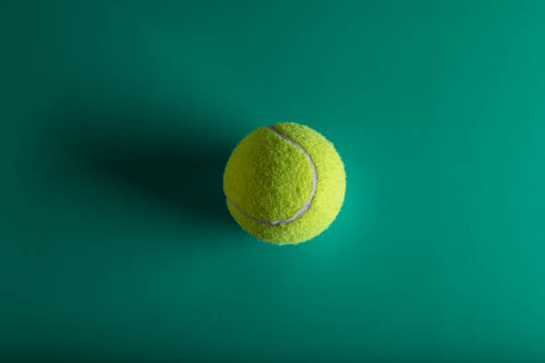 Tennis ball with shadow on green background