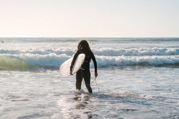 istock latin surfer getting into the ocean to surf the waves 1356222453