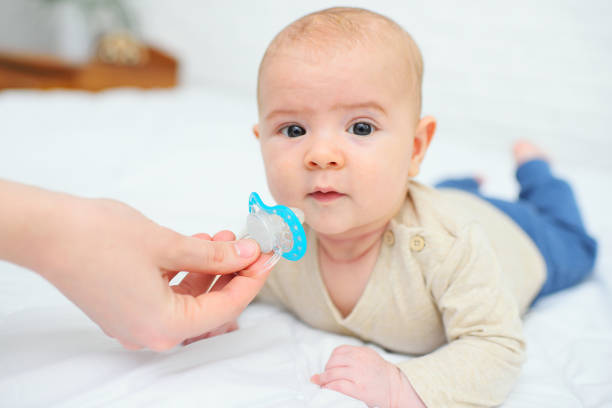istock hand gives a pacifier to her baby son on a white background 1356223242