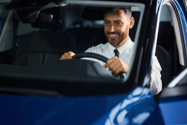 istock Smiling bearded man choosing car at showroom 1356224134