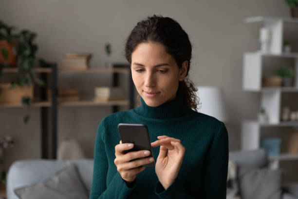 istock Focused millennial latin female use smartphone to work at internet 1356225335
