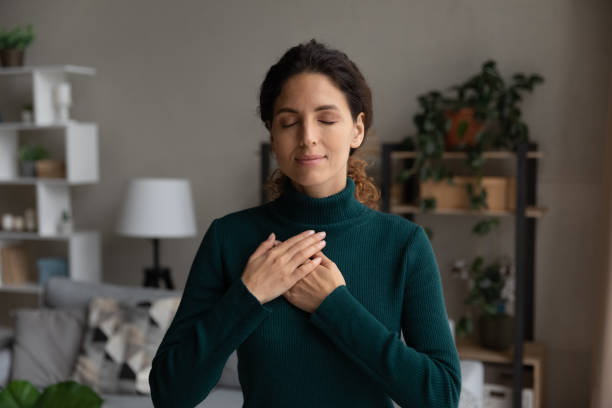 pacífica joven latina pone las manos en el corazón gracias a dios - heart shape loneliness women praying fotografías e imágenes de stock