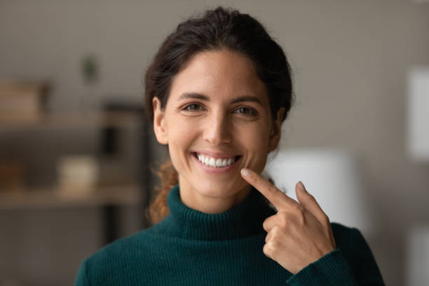 smiling hispanic lady look at camera point on white teeth - gums imagens e fotografias de stock