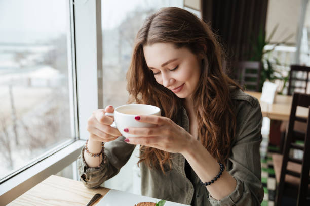istock Cute cheerful young beautiful lady sitting in cafe drinking tea. 1356225944