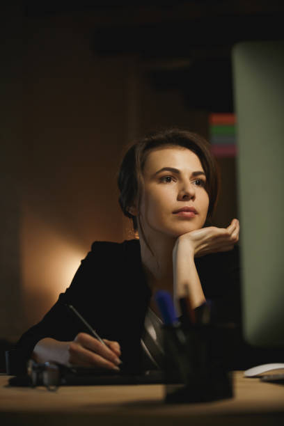 istock Concentrated young lady designer sitting in office at night 1356227444