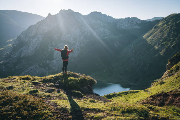 istock Female hiker relaxes on grassy mountain ridge 1356228431