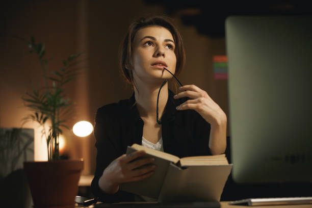 istock Concentrated young lady designer reading book. 1356228439