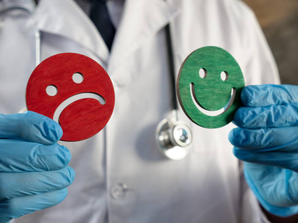 istock Patient satisfaction survey. Doctor holds joyful and sad emoticons. 1356228571