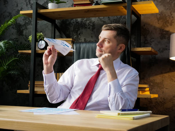 Procrastination and workplace boredom. An employee launches a paper airplane. stock photo