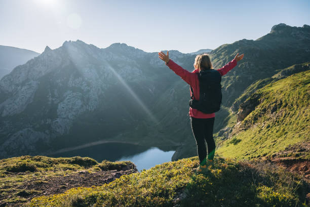 istock Female hiker relaxes on grassy mountain ridge 1356228666