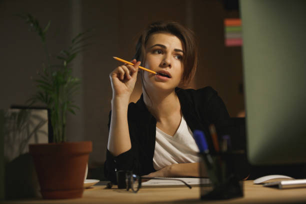 istock Serious young lady designer sitting in office at night 1356228738