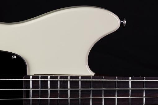 front body of a white electric bass on black background.