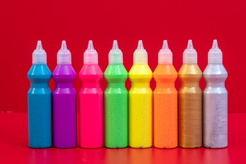 Colorful paints on red background in plastic tubes