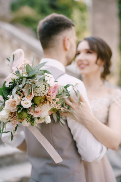 istock Bride with a bouquet hugs groom on the stone steps. Portrait 1356234196