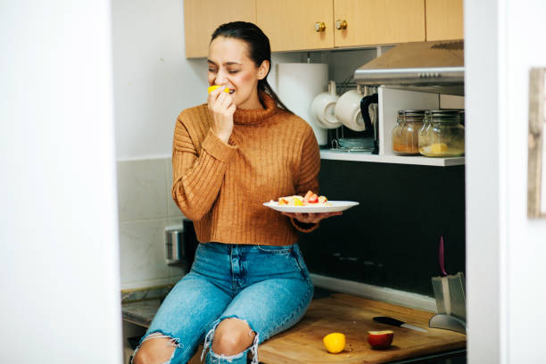 istock woman eating apple while standing in the kitchen 1356236916