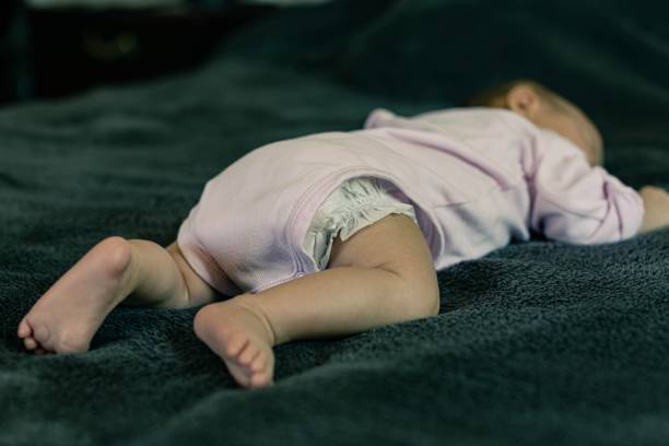 A baby sleeping in a dangerous position. Sudden infant death syndrome. stock photo